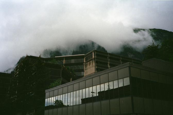 A golden, brutalist building with misty mountains in the background