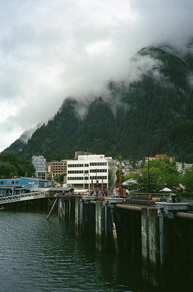 Some buildings along the dock in Juneau, backed by the tall, misty mountains